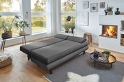 Graues Funktionssofa in einem modernen Wohnzimmer mit Blick auf den Garten, umgeben von Pflanzen und einem Kamin.