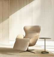 Beiger Relaxsessel in einem modernen Raum, seitliche Perspektive, mit einem kleinen runden Beistelltisch.