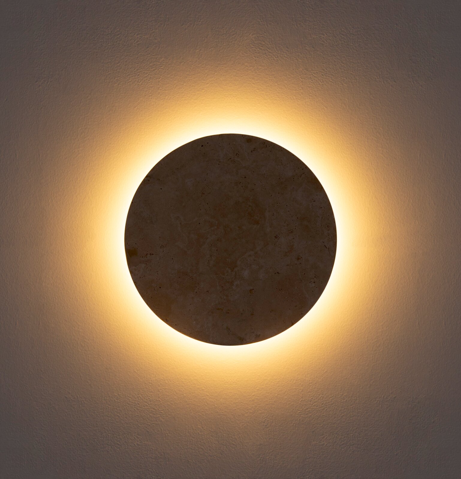 Runde Wandleuchte mit Steinoptik und warmweißem indirektem Halo-Licht an strukturierter Wand, Frontalansicht
