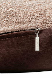 Nahaufnahme einer Zierkissenhülle mit weicher, strukturierter Oberfläche in Beige und einem braunen Reißverschluss mit JOOP!-Logo.