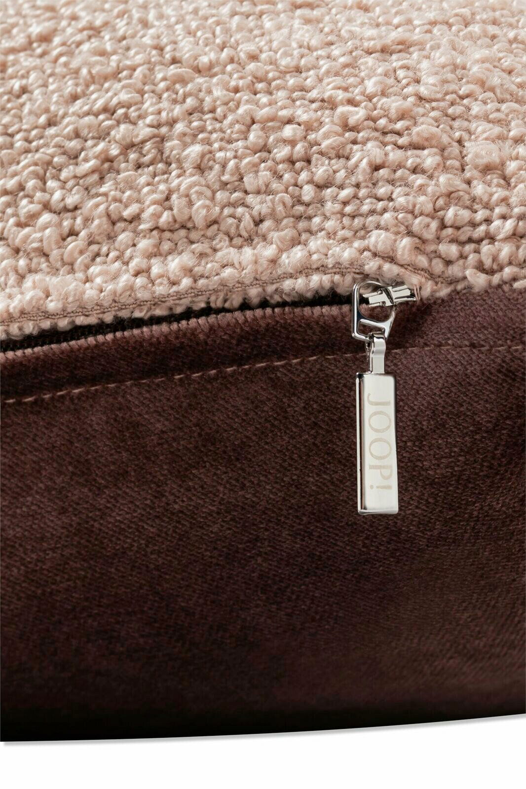 Nahaufnahme einer Zierkissenhülle mit weicher, strukturierter Oberfläche in Beige und einem braunen Reißverschluss mit JOOP!-Logo.