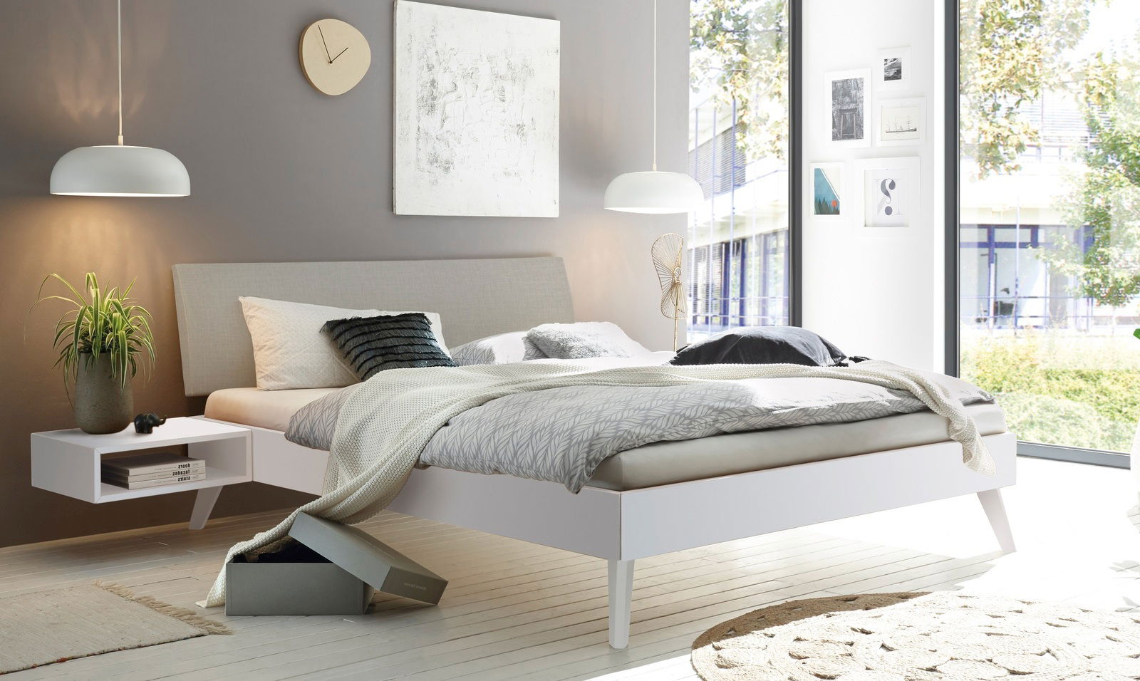 Modernes Schlafzimmer mit gepolstertem Kopfteil, seitlicher Perspektive, helle Farben und minimalistisches Design.
