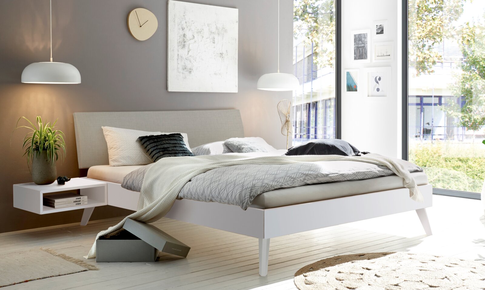 Modernes Schlafzimmer mit gepolstertem Kopfteil, seitlicher Perspektive, helle Farben und minimalistisches Design.