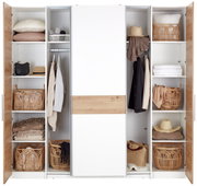Moderner Dreh- und Schwebetürenschrank mit vier Türen, teilweise geöffnet, zeigt eine stilvolle Kombination aus Holz- und Weißtönen. Der Schrank ist mit Körben, Kleidung und Accessoires gefüllt. Frontalansicht.