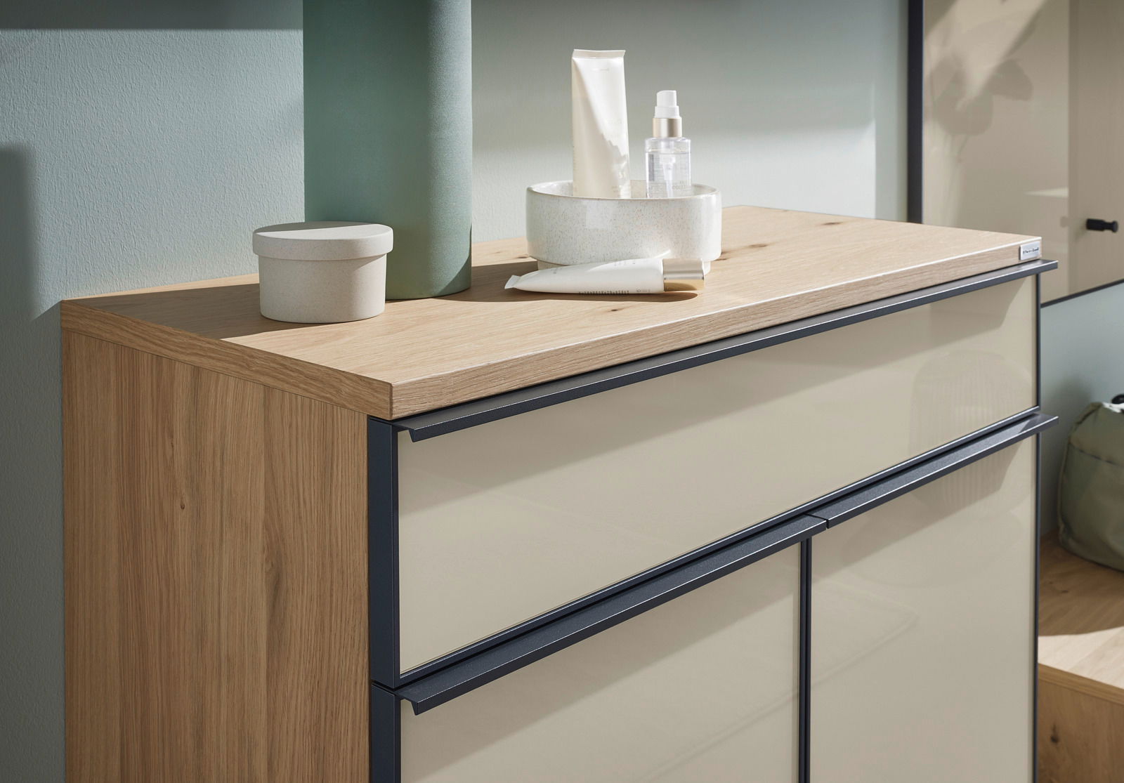 Nahaufnahme eines modernen Schuhschranks mit Holzoberfläche und cremefarbenen Fronten, dekoriert mit Pflegeprodukten und Accessoires.