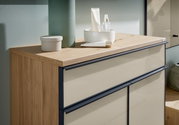 Close-up van een moderne schoenenkast met houten afwerking en crèmekleurige fronten, versierd met verzorgingsproducten en accessoires.
