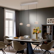 Moderne hanglamp met drie lampen in wit boven een eettafel in een stijlvolle eetkamer, vooraanzicht met een lichte onderhoek