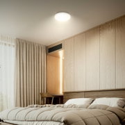 Moderne slaapkamer met houten wandpanelen, groot bed met beige dekbed en kussens, gordijnen en ronde plafondlamp, gezien vanuit een lage hoek vanaf het bed richting het plafond en de wand.