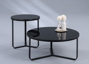 Zwei moderne Tische mit schwarzer Glasplatte und Metallgestell, einer als Beistelltisch und der andere als Couchtisch, aus seitlicher Perspektive fotografiert.