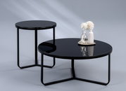 Twee moderne tafels met een zwart glazen blad en een metalen onderstel, de ene als bijzettafel en de andere als salontafel, gefotografeerd vanuit een zijaanzicht.