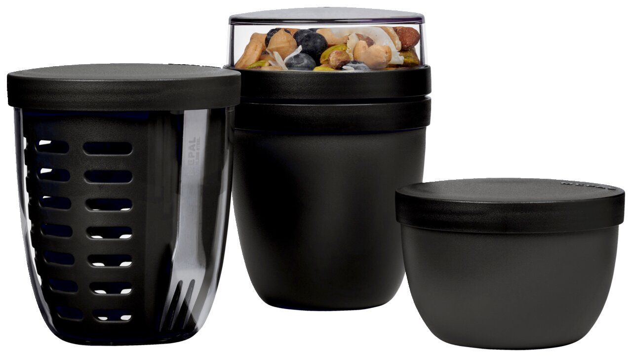 Mepal Snackpot-set, 3-delig ELLIPSE Dreiteiliges schwarzes Snackpot-Set aus Kunststoff, bestehend aus einem Behälter mit Gabel, einem Behälter mit transparentem Deckel gefüllt mit Nüssen und einem kleineren Behälter, seitliche Perspektive.