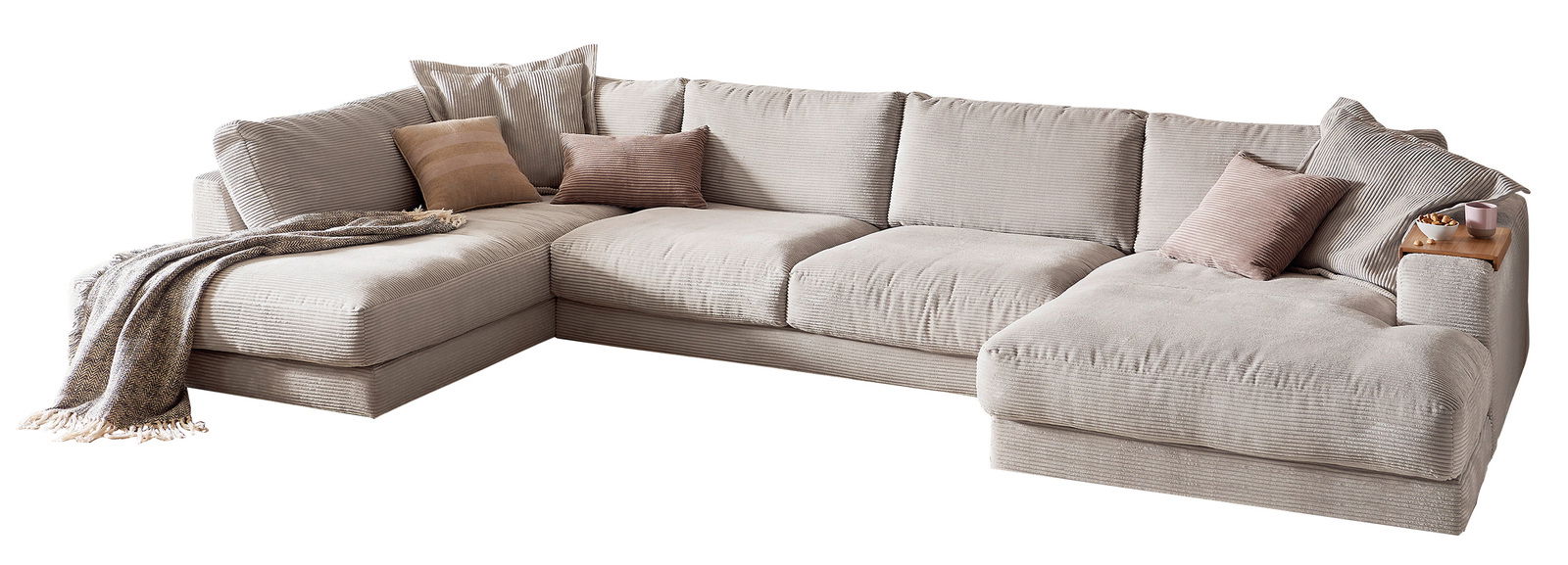 Große, beige Polsterrundecke in L-Form mit mehreren Kissen und einer Decke, aus der Perspektive von vorne rechts betrachtet.