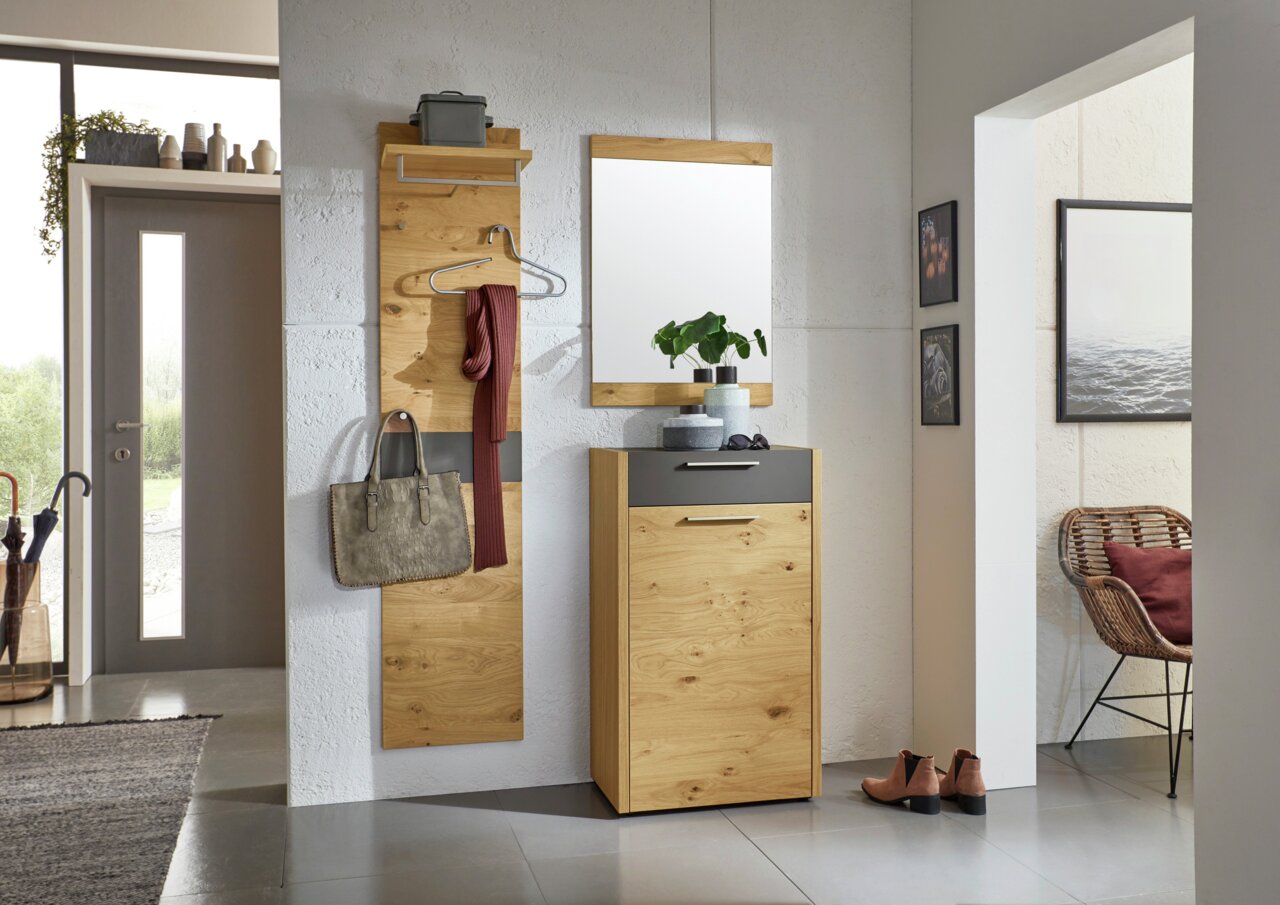 Fluransicht mit modernem Garderoben-Set aus Holz, bestehend aus einem Wandpaneel mit Haken und Ablage, einem Spiegel und einem Schuhschrank. Perspektive von vorne.