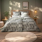 Bett mit modernem, geometrischem Muster in Grau- und Grüntönen, umgeben von stilvoller Dekoration in einem gemütlichen Schlafzimmer. Frontalansicht.