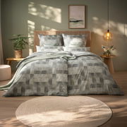 Bett mit modernem, geometrischem Muster in Grau- und Grüntönen, umgeben von stilvoller Dekoration in einem gemütlichen Schlafzimmer. Frontalansicht.