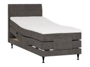 Donkergrijs gestoffeerd elektrisch verstelbaar bed met hoog hoofdbord en witte matras, schuin van voren weergegeven