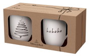 Zwei weiße Tassen in einer Geschenkbox mit Sichtfenster, eine Tasse mit einem stilisierten Weihnachtsbaum und die andere mit 'ho ho ho' Schriftzug, seitliche Perspektive.