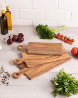 Holzgriffbrett in einer Küche, umgeben von frischen Zutaten wie Tomaten, Zwiebeln und Kräutern, aus der Vogelperspektive fotografiert.