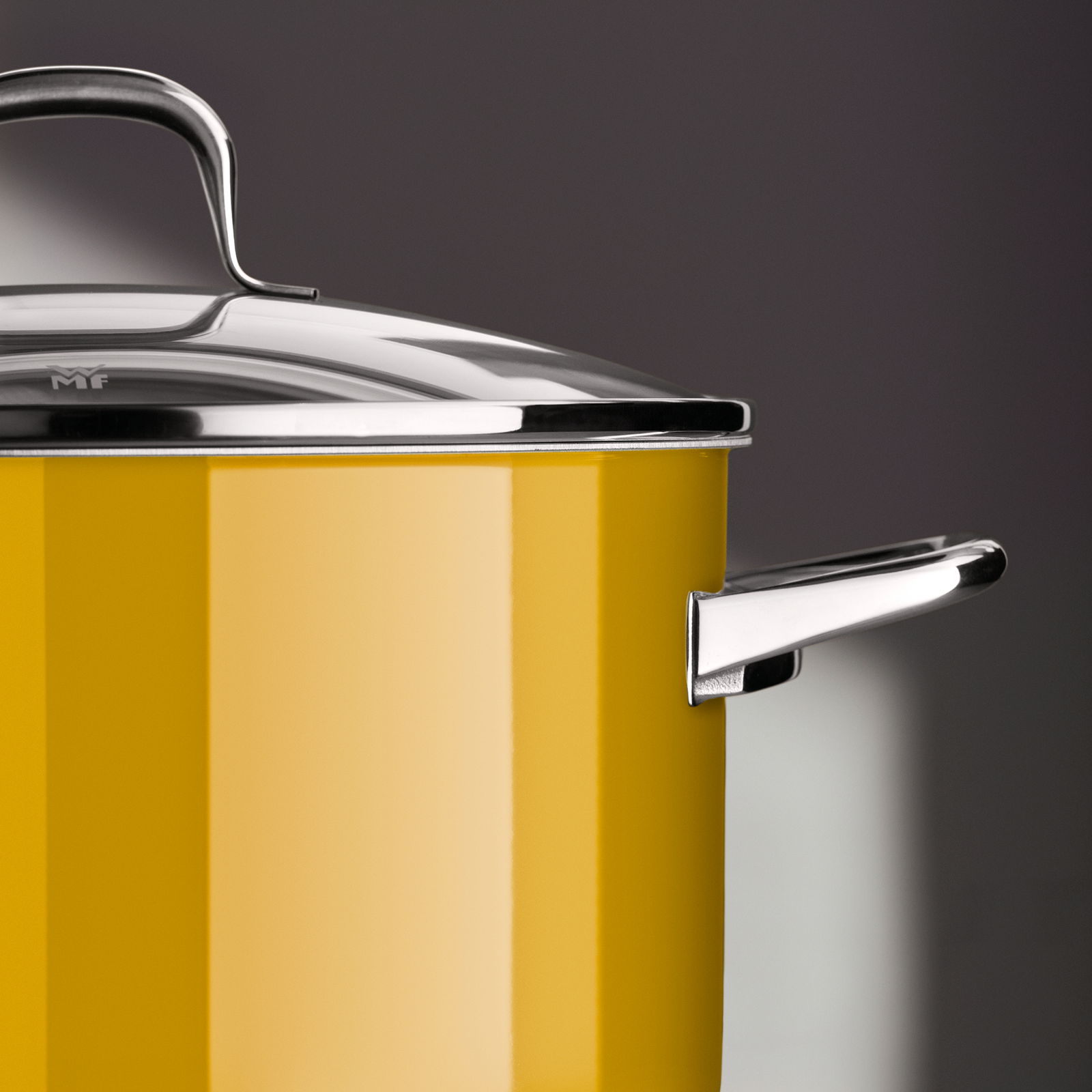 Nahaufnahme eines gelben Kochtopfs mit Edelstahlgriff und Deckel, seitliche Perspektive