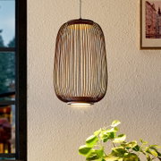 Hängelampe mit ovalem, käfigartigem Lampenschirm aus dunklem Holz/Lamellen und warmem Licht, frontal in leicht seitlicher Innenraumansicht vor heller Wand