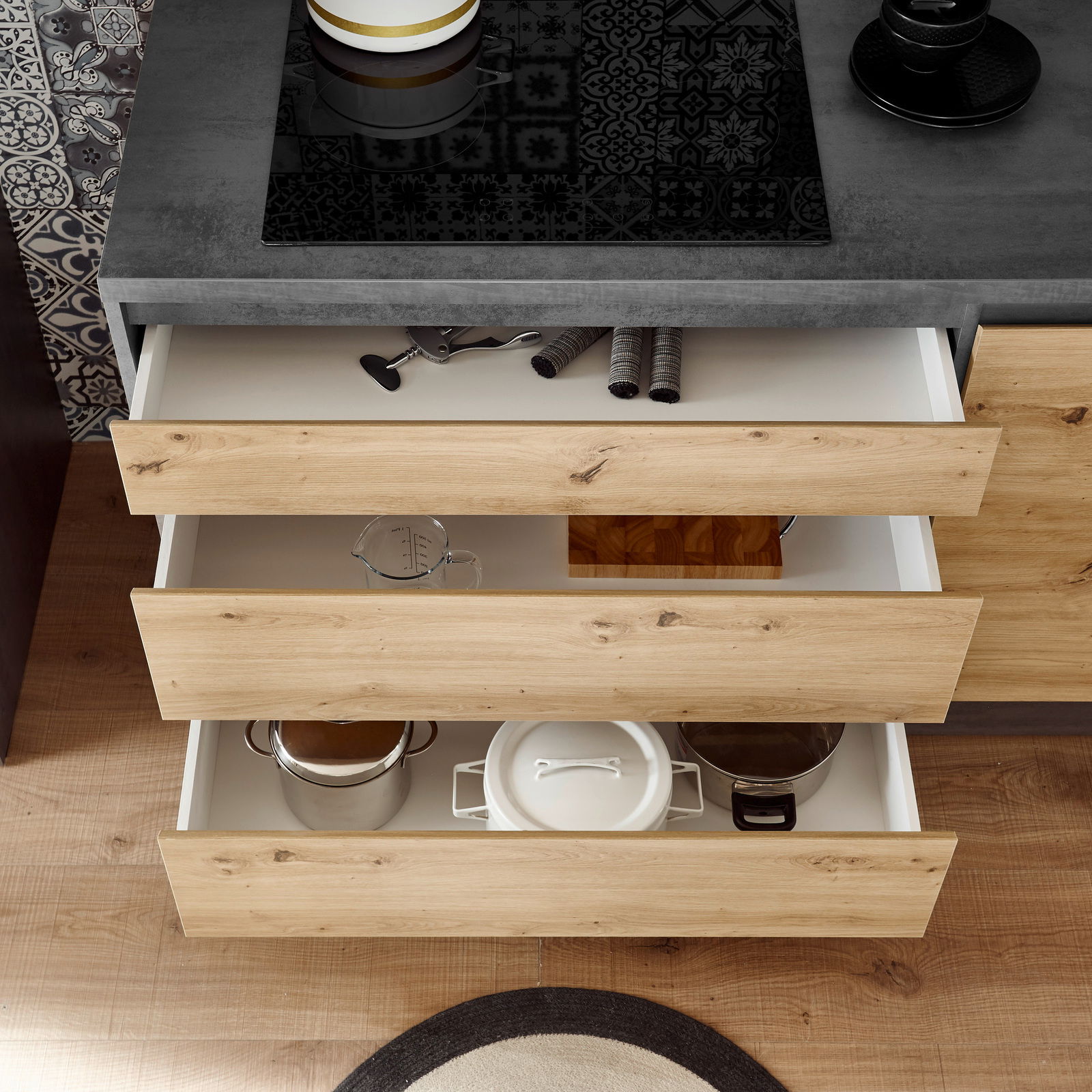 Küchenblock mit offenen Schubladen aus Holzoptik, gefüllt mit Küchenutensilien, aus der Vogelperspektive betrachtet.