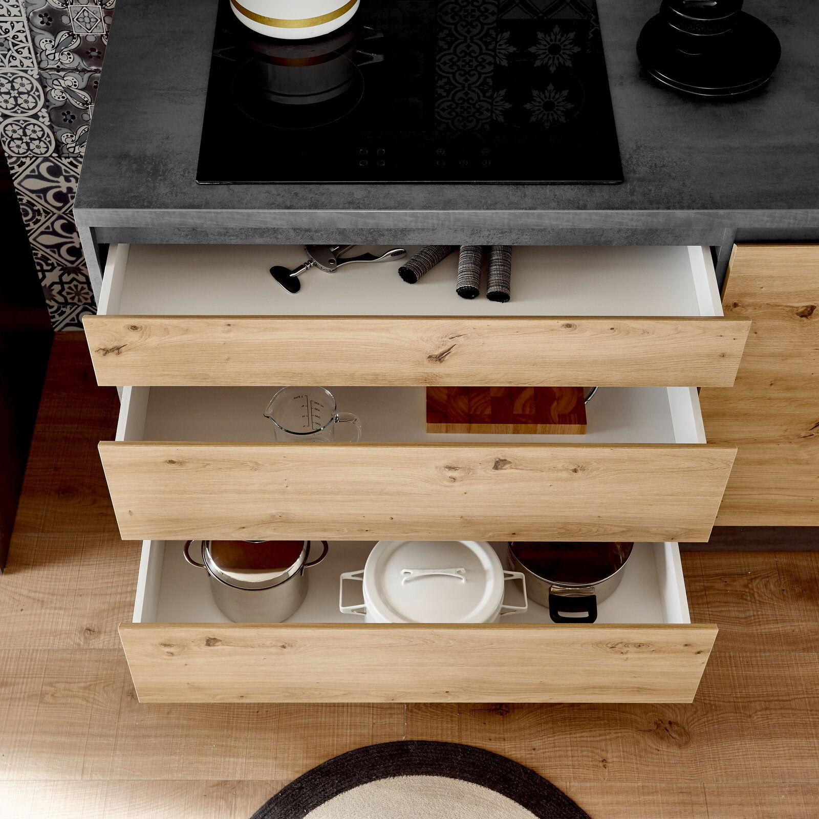 Küchenblock mit offenen Schubladen aus Holzoptik, gefüllt mit Küchenutensilien, aus der Vogelperspektive betrachtet.