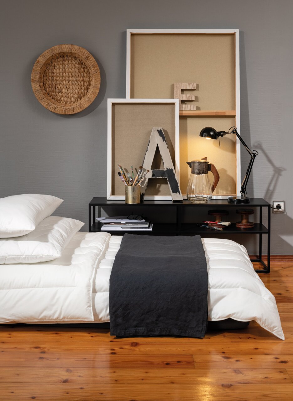 Centa Star Ganzjahresbettdecke INSPIRATION Ganzjahresbett 200x200cm in einem modernen Schlafzimmer, seitliche Perspektive mit dekorativem Regal im Hintergrund.