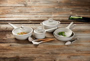 Kochset aus acht Teilen, bestehend aus Töpfen und Pfannen mit Deckeln, auf einer Holzoberfläche von oben fotografiert.