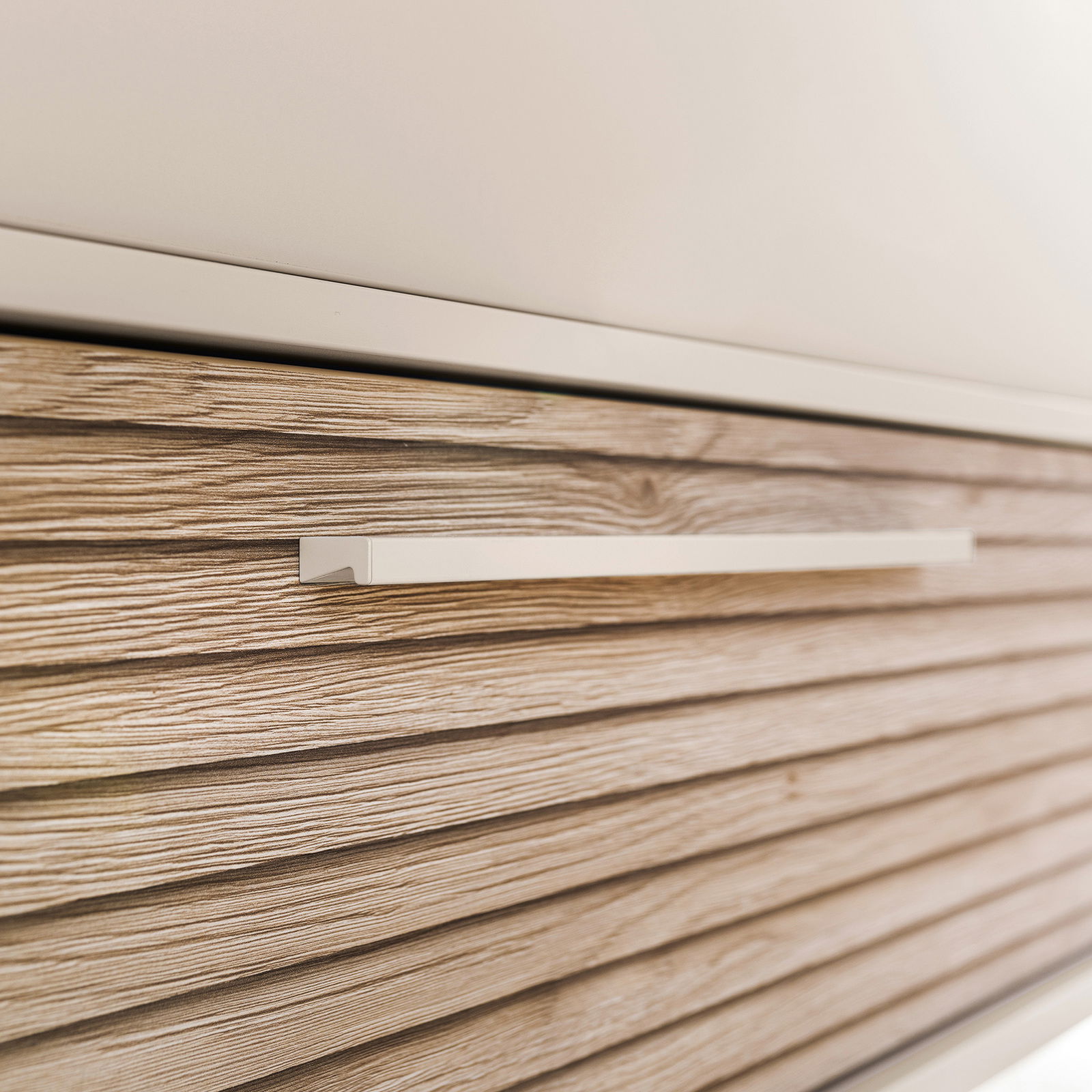 Nahaufnahme einer Kommode mit horizontalen Holzmaserungen und einem modernen, schlichten Griff.