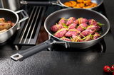 Bratpfanne 28cm Silence Pro mit schwarzem Griff, gefüllt mit rosa Fleisch und Gemüse, auf einem Herd von schräg oben fotografiert.