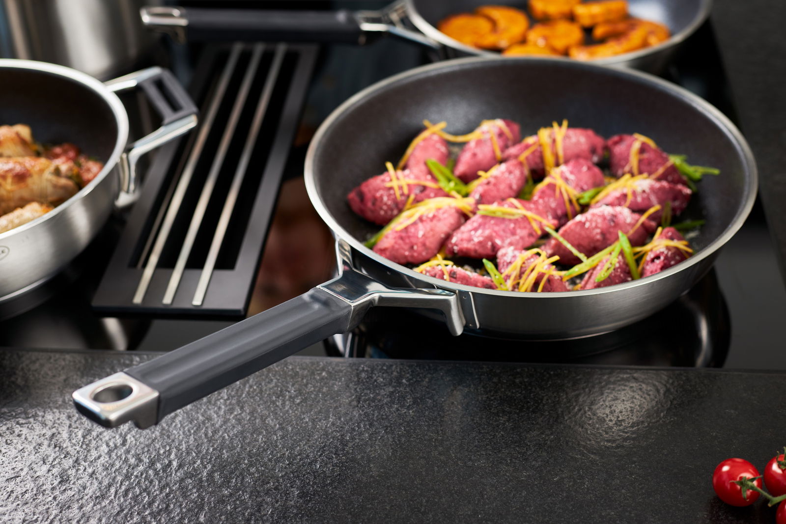 Bratpfanne 28cm Silence Pro mit schwarzem Griff, gefüllt mit rosa Fleisch und Gemüse, auf einem Herd von schräg oben fotografiert.