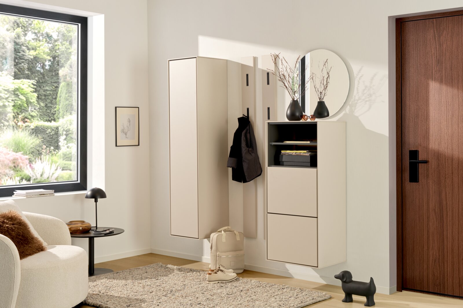Voleo Garderobeset RENO Moderne, lichte halinrichting met een aan de muur bevestigde witte garderobekast, een paneel met haken en een schoenenkast met ronde spiegel, gefotografeerd vanuit een licht schuin perspectief.