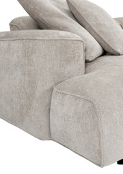 Detailaufnahme eines hellbeigen Stoffsofas mit breiter Armlehne und weichen Rückenkissen, Perspektive schräg von vorne links