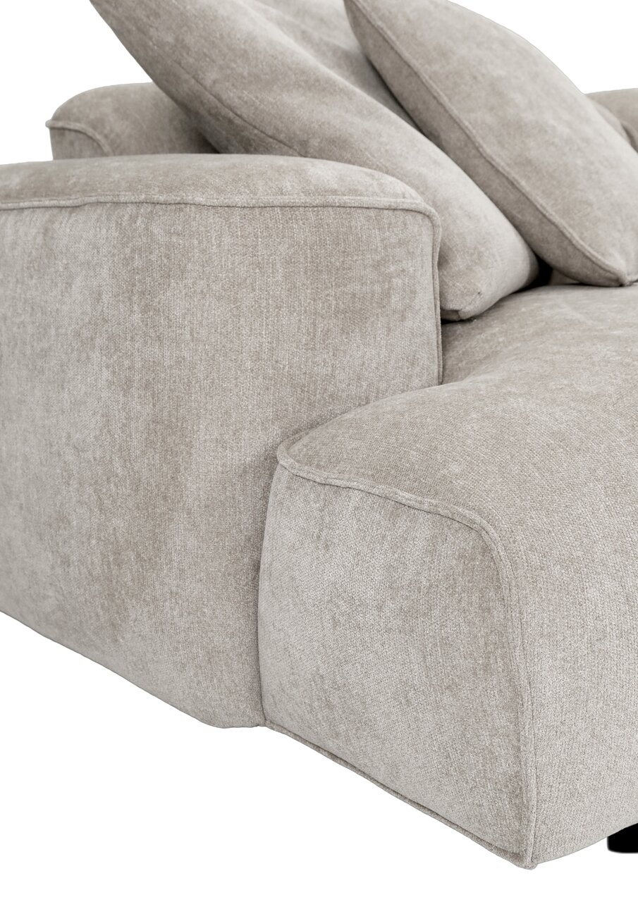 Detailaufnahme eines hellbeigen Stoffsofas mit breiter Armlehne und weichen Rückenkissen, Perspektive schräg von vorne links
