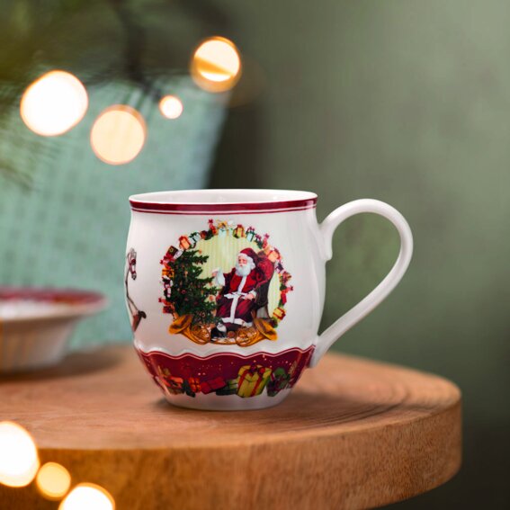Jumbobecher mit Weihnachtsmotiv, zeigt den Weihnachtsmann neben einem geschmückten Baum, seitliche Perspektive