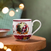 Jumbobecher mit Weihnachtsmotiv, zeigt den Weihnachtsmann neben einem geschmückten Baum, seitliche Perspektive
