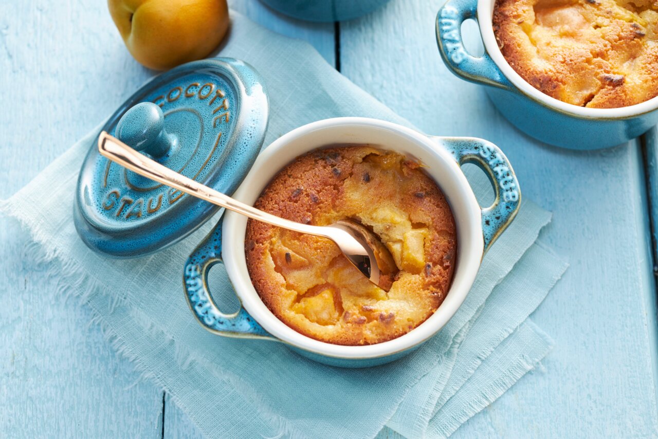 Mini-Cocotte in Türkis mit Deckel, gefüllt mit einem gebackenen Dessert, aus der Vogelperspektive fotografiert.