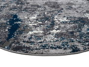 Nahaufnahme eines Designer-Teppichs mit abstraktem Muster in Grau- und Blautönen, perspektivisch von der Seite aufgenommen.