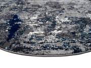 Nahaufnahme eines Designer-Teppichs mit abstraktem Muster in Grau- und Blautönen, perspektivisch von der Seite aufgenommen.