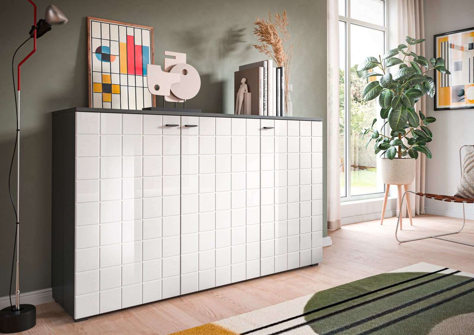 Modernes Sideboard mit glänzender, weißer Kacheloptik und dunkler Oberseite, dekoriert mit Kunstobjekten und Büchern, in einem stilvoll eingerichteten Raum mit Blick auf ein großes Fenster.