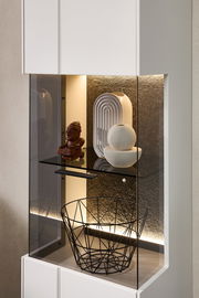 Detailansicht einer modernen Vitrine mit LED-Beleuchtung, dekoriert mit Skulpturen und einem Drahtkorb.