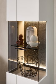 Detailfoto van een moderne vitrinekast met ledverlichting, versierd met beeldjes en een draadmand.