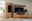 Frontale Ansicht einer modernen Wandkombination aus Holz mit TV-Schrank, Regal und Vitrine, dekoriert mit Pflanzen und Accessoires.
