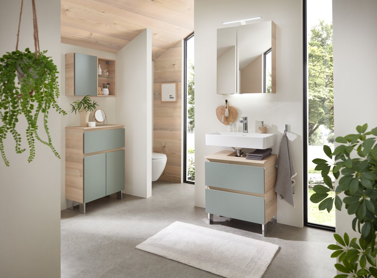 Sadena Sockelfuß-Set ZUBEHÖR Modernes Badezimmer mit Holz- und Pastellakzenten, Blick auf Waschtisch mit Spiegel und Schrank.