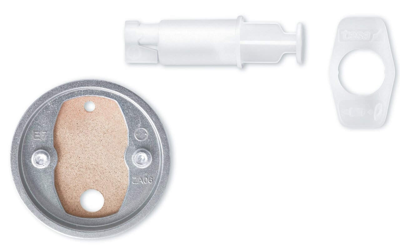 Tesa Bevestigingsadapter BK20 Bovenaanzicht van de tesa-bevestigingsadapter BK20 met ronde metalen plaat, witte kunststofadapter en doorzichtige kunststofring.