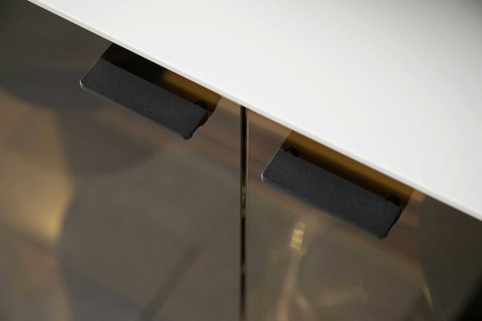 Nahaufnahme eines Sideboards mit weißer Oberfläche und schwarzen Griffen, aus der Vogelperspektive fotografiert.