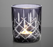 Graues Windlicht mit Schliffmuster, frontal fotografiert, mit brennendem Teelicht im Inneren.