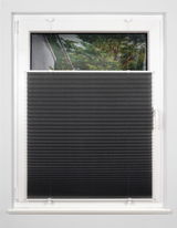 Schwarzes Plissee gefädelt, halb heruntergelassen an einem weißen Fenster, von innen fotografiert.