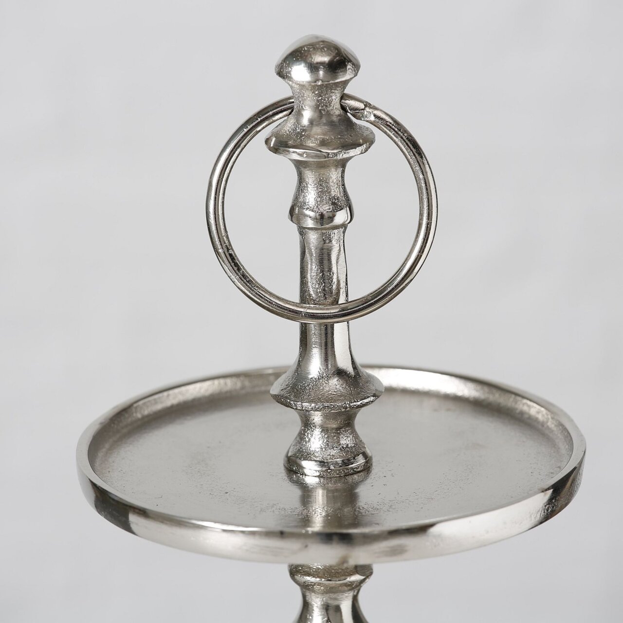 Boltze Deko-Etagere 3er H50cm VALOMI Nahaufnahme einer silbernen Deko-Etagere mit drei Ebenen, elegantes Design mit rundem Griff oben, seitliche Perspektive.