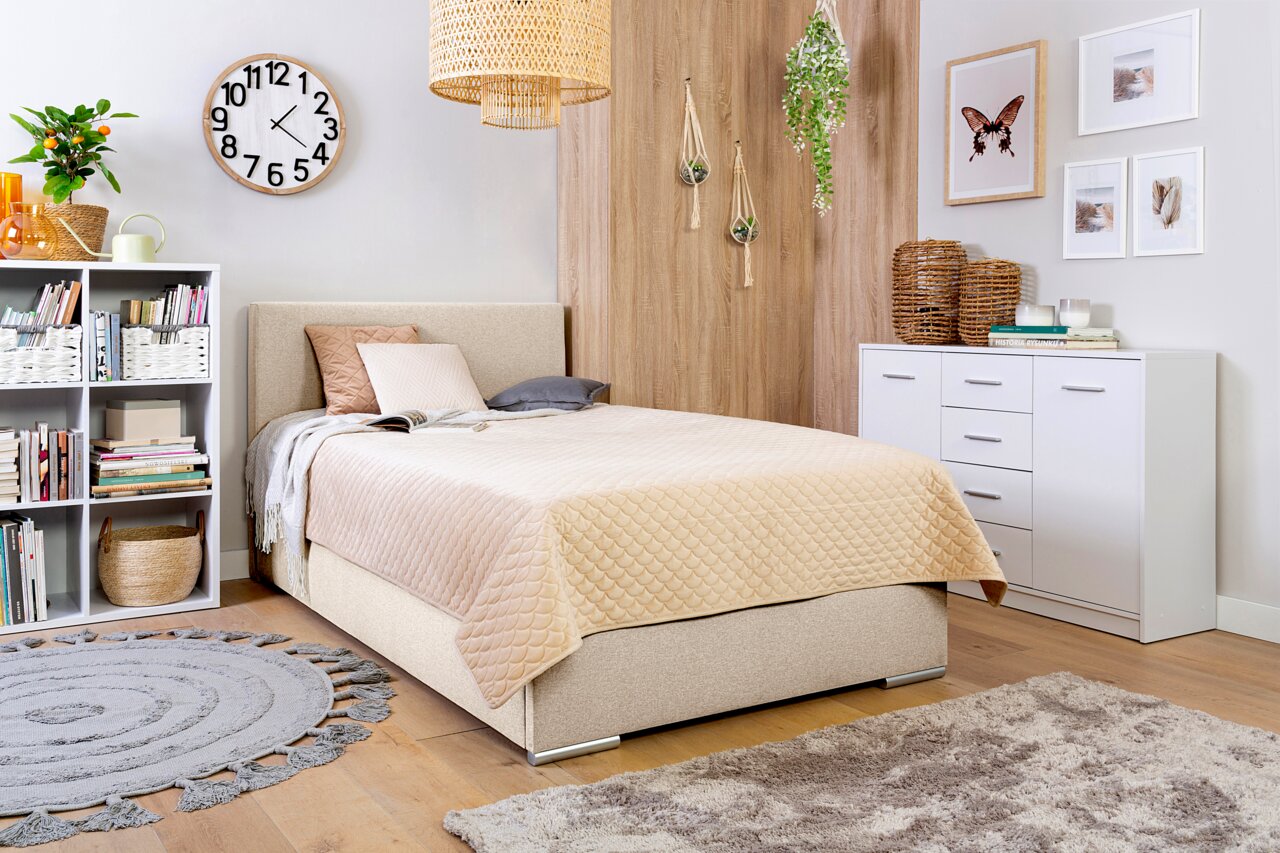 Gezellige slaapkamer met een boxbed van 140 cm, beige beddengoed, boekenkast, wandklok en decoraties, zijaanzicht